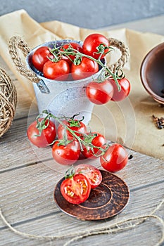 Bucket of tomatoes and half cut tomato on wooden table