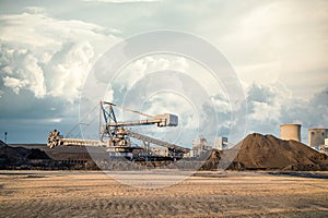 Bucket wheel machine large surface mining excavator at UK power station working in open cast heaps of coal with cooling towers