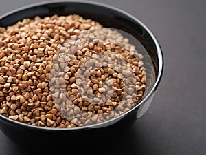 Buckwheat in a black bowl on a black surface
