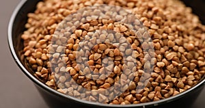 Buckwheat in a black bowl on a black surface.