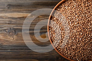 Buckwheat in a bowl on a brown textured wood background.