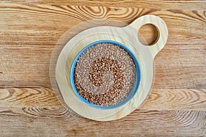 Buckwheat in a bowl on wooden background, top view