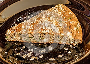 Buckwheat flour and spinach pie with sesame and flakes on black plate