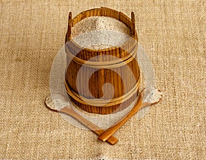 Buckwheat flour in wooden canister with two wooden spoons on sackcloth