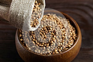 Buckwheat groats hulled seeds in bowl and burlap bag on wooden table photo