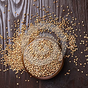 Buckwheat groats hulled seeds in bowl on wooden background, top view photo
