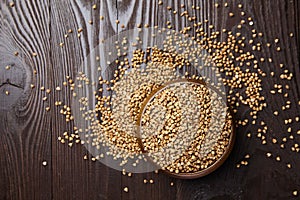 Buckwheat groats hulled seeds in bowl on wooden background, top view photo