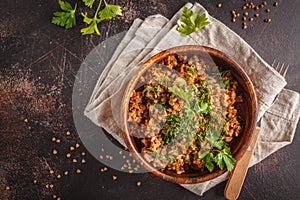 Buckwheat with meat in a wooden bowl on a dark background, top v photo