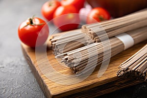 Buckwheat pasta with cherry tomatoes on a black textured marble background.