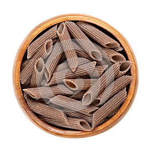 Buckwheat penne, gluten free whole grain pasta, in a wooden bowl