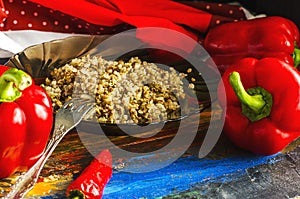 Buckwheat porridge in a black transparent plate with red peppers.