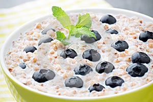 Buckwheat porridge in a bowl with mint leaves and blueberries. photo