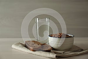 Buckwheat porridge, bread and glass of water on white wooden table. Fasting meals for Lent season