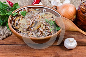 Buckwheat porridge with mushrooms in clay dish among the ingredients