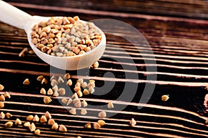 Buckwheat raw seeds in wooden spoon on wood table. Healthy eating background