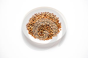 Buckwheat in a saucer, on a white background