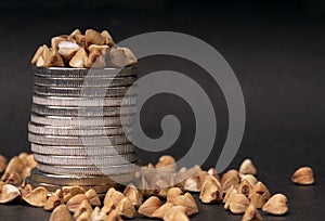 Buckwheat and a stack of coins on a black background