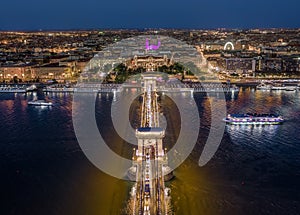 Budapest, Hungary - Aerial view of illuminated Szechenyi Chain Bridge with St. Stephen`s Basilica, ferris wheel and cruise ships