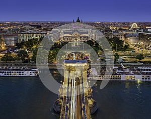 Budapest, Hungary - Aerial view of Szechenyi Chain Bridge with St. Stephen`s Basilica, ferris wheel and cruise ships at blue hour