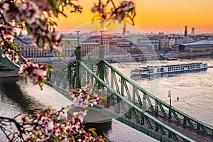 Budapest, Hungary - Beautiful spring sunrise at Liberty Bridge with cruise ship on River Danube and Cherry Blossom