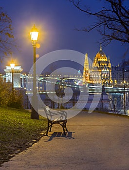 Budapest, Hungary - Bench and lamp post in a park at Buda district with Parliament of Hungary adn Szechenyi Chain Bridge photo