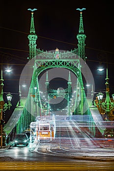 Budapest, Hungary - Festively decorated light tram fenyvillamos on the move at Liberty Bridge Szabadsag hid by night