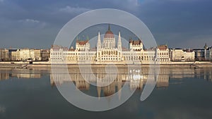 Budapest, Hungary - Hungarian Parliament building with warm sunset lights, reflections and motorboat on River Danube
