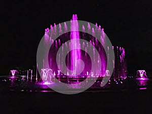 Purple color musical fountain. Magnificent night show of colorful lights, laser beams,