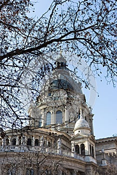 Budapest, Hungary - 02/19/2018: St. Stephen`s Cathedral with bared tree foreground against clear blue sky. Religious architecture.