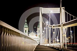 Budapest modern white bridge with baroque church in background.