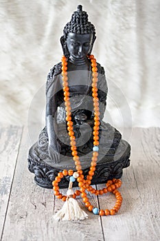 Buddah statue with orange beads for reading mantras