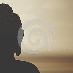 Buddha in backlight in meditation towards the rising sun