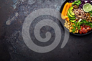 Buddha bowl dish with brown rice, avocado, pepper, tomato, cucumber, red cabbage, chickpea, fresh lettuce salad and walnuts. Healt