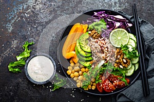 Buddha bowl dish with brown rice, avocado, pepper, tomato, cucumber, red cabbage, chickpea, fresh lettuce salad and walnuts. Healt