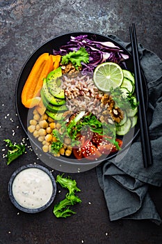 Buddha bowl dish with brown rice, avocado, pepper, tomato, cucumber, red cabbage, chickpea, fresh lettuce salad and walnuts. Healt