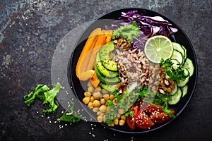 Buddha bowl dish with brown rice, avocado, pepper, tomato, cucumber, red cabbage, chickpea, fresh lettuce salad and walnuts. Healt