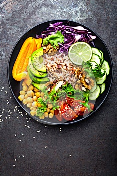 Buddha bowl dish with brown rice, avocado, pepper, tomato, cucumber, red cabbage, chickpea, fresh lettuce salad and walnuts. Healt