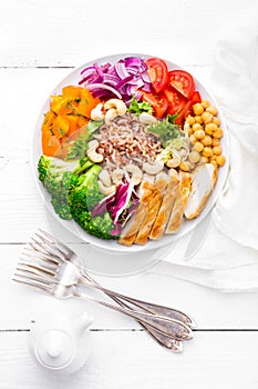 Buddha bowl dish with chicken fillet, brown rice, pepper, tomato, broccoli, onion, chickpea, fresh lettuce salad, cashew and walnu