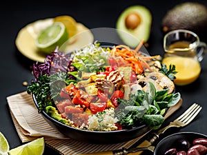 Buddha bowl of mixed vegetables, tofu cheese and groat on a black background. Gourmet and nutritious vegan meal.