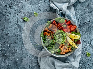 Buddha bowl salad with baked sweet potatoes, chickpeas, broccoli, tomatoes, greens, avocado, pea sprouts on light blue background