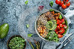 Buddha bowl salad with baked sweet potatoes, chickpeas, quinoa, tomatoes, arugula, avocado, sprouts on light blue background