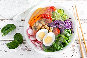 Buddha bowl salad with chickpeas, sweet pepper, tomato, cucumber, red cabbage kale, fresh radish, spinach leaves and boiled egg