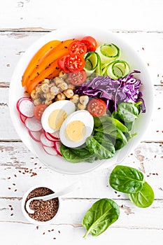 Buddha bowl salad with chickpeas, sweet pepper, tomato, cucumber, red cabbage kale, fresh radish, spinach leaves and boiled egg