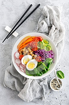 Buddha bowl salad with chickpeas, sweet pepper, tomato, cucumber, red cabbage kale, fresh radish, spinach leaves and boiled egg