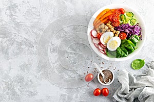 Buddha bowl salad with chickpeas, sweet pepper, tomato, cucumber, red cabbage kale, fresh radish, spinach leaves and boiled egg