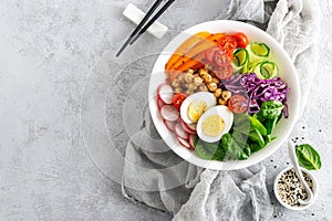 Buddha bowl salad with chickpeas, sweet pepper, tomato, cucumber, red cabbage kale, fresh radish, spinach leaves and boiled egg