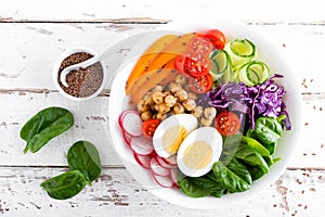 Buddha bowl salad with chickpeas, sweet pepper, tomato, cucumber, red cabbage kale, fresh radish, spinach leaves and boiled egg