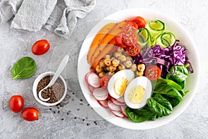 Buddha bowl salad with chickpeas, sweet pepper, tomato, cucumber, red cabbage kale, fresh radish, spinach leaves and boiled egg