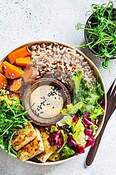 Buddha bowl with tofu, avocado, rice, seedlings, sweet potato and tahini dressing