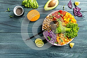 Buddha bowl vegetarian, vegan dish with avocado, tomato, red cabbage, chickpea, fresh lettuce salad, pumpkin, persimmon. Healthy